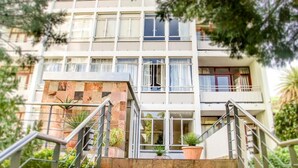 A multi-story building with a modern architectural design, featuring a central staircase with metal railings and potted plants. - 438 St Martini (Cape Town)