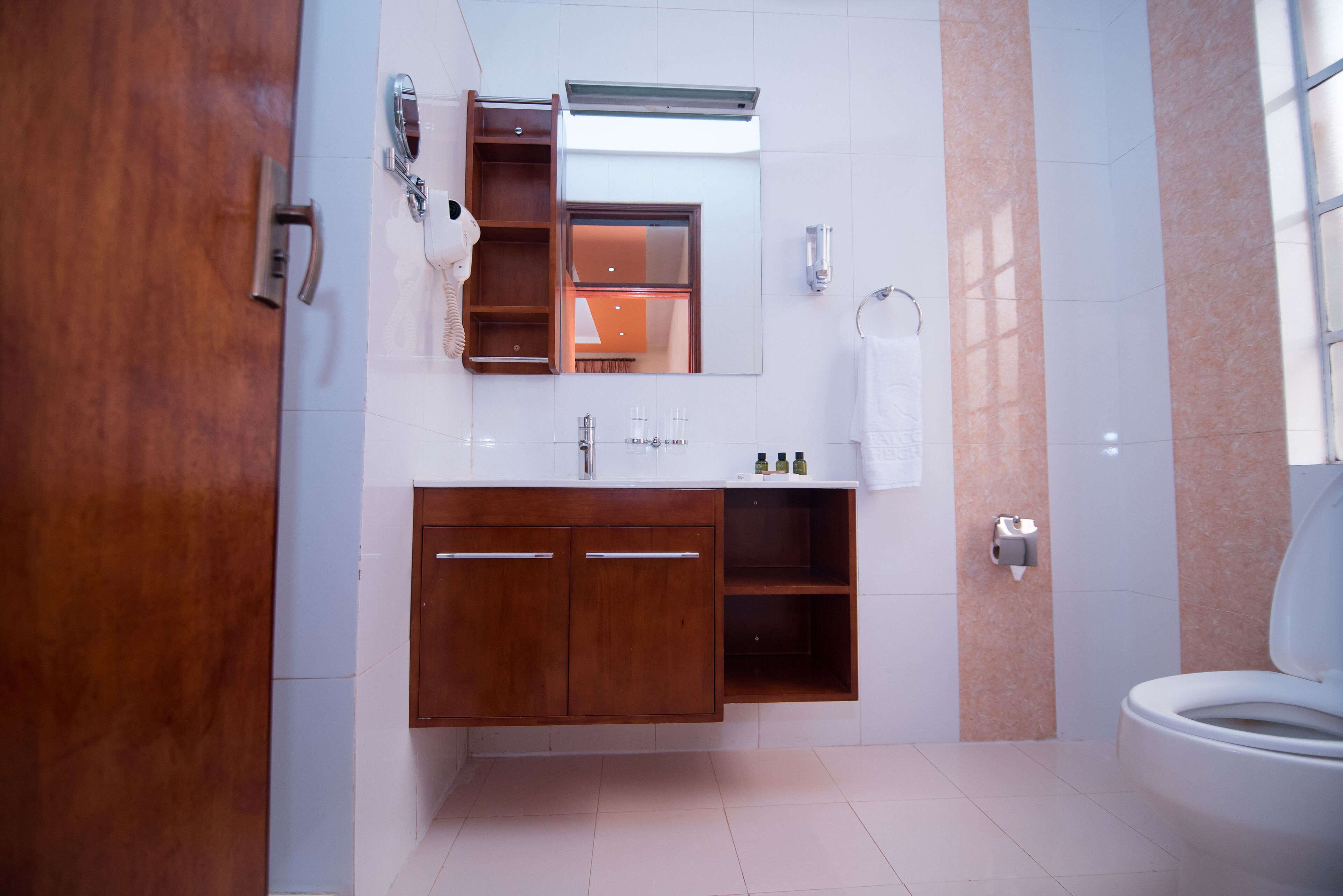 Une salle de bain moderne avec un meuble-lavabo en bois, un miroir, un porte-serviettes et des toilettes.