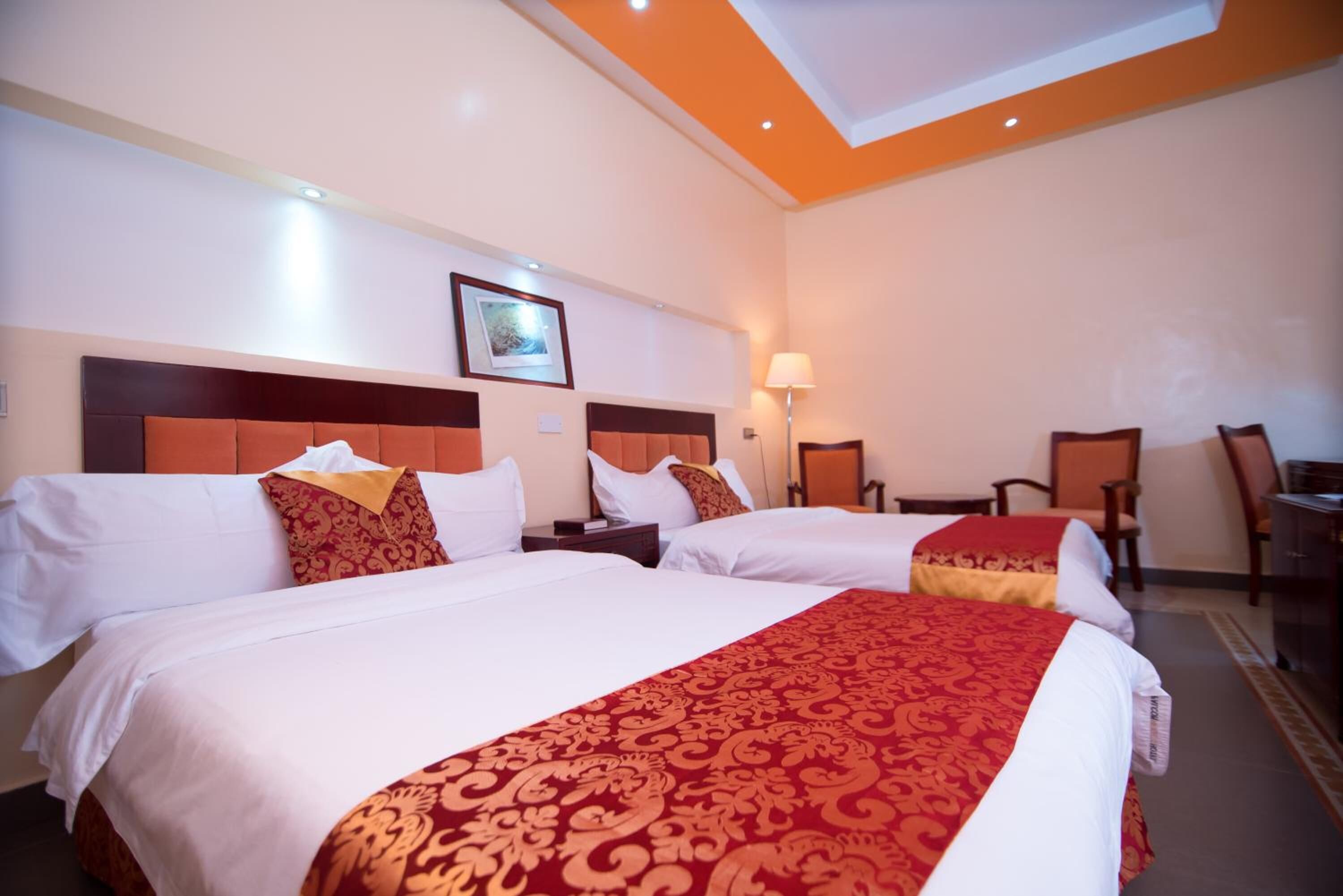 A hotel room with two beds, a desk, and a chair.