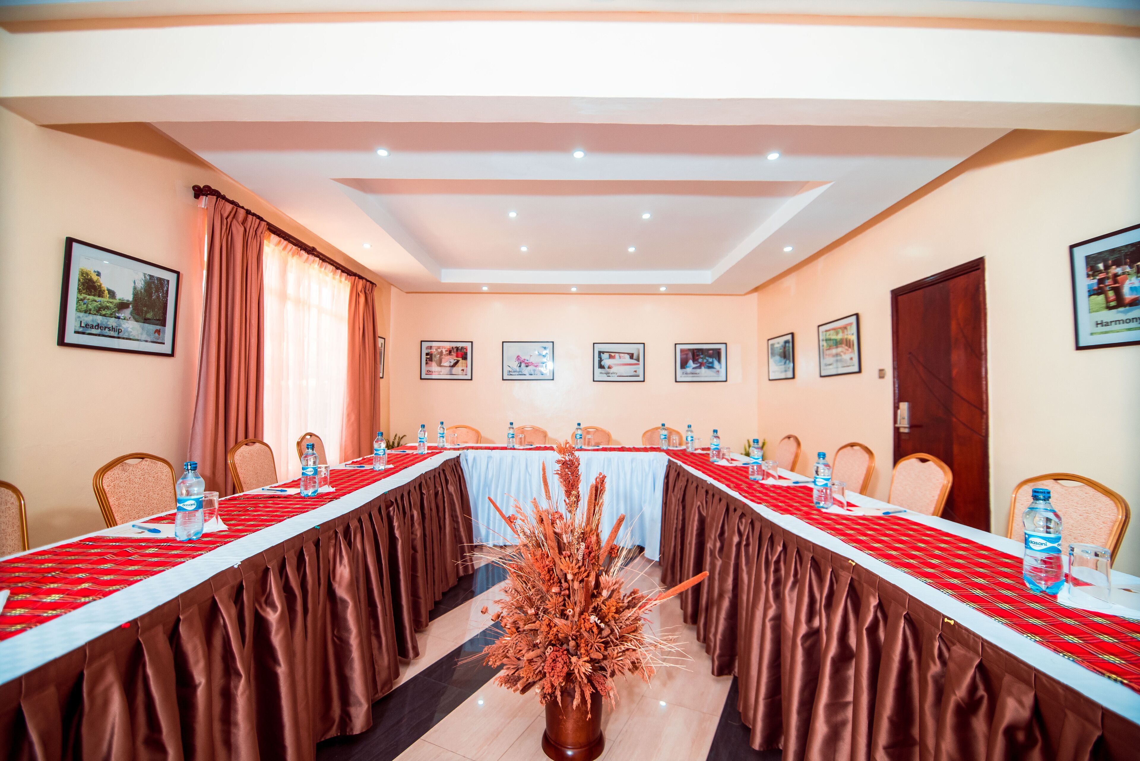 Une salle de conférence avec une longue table, des chaises et des tableaux encadrés accrochés aux murs.