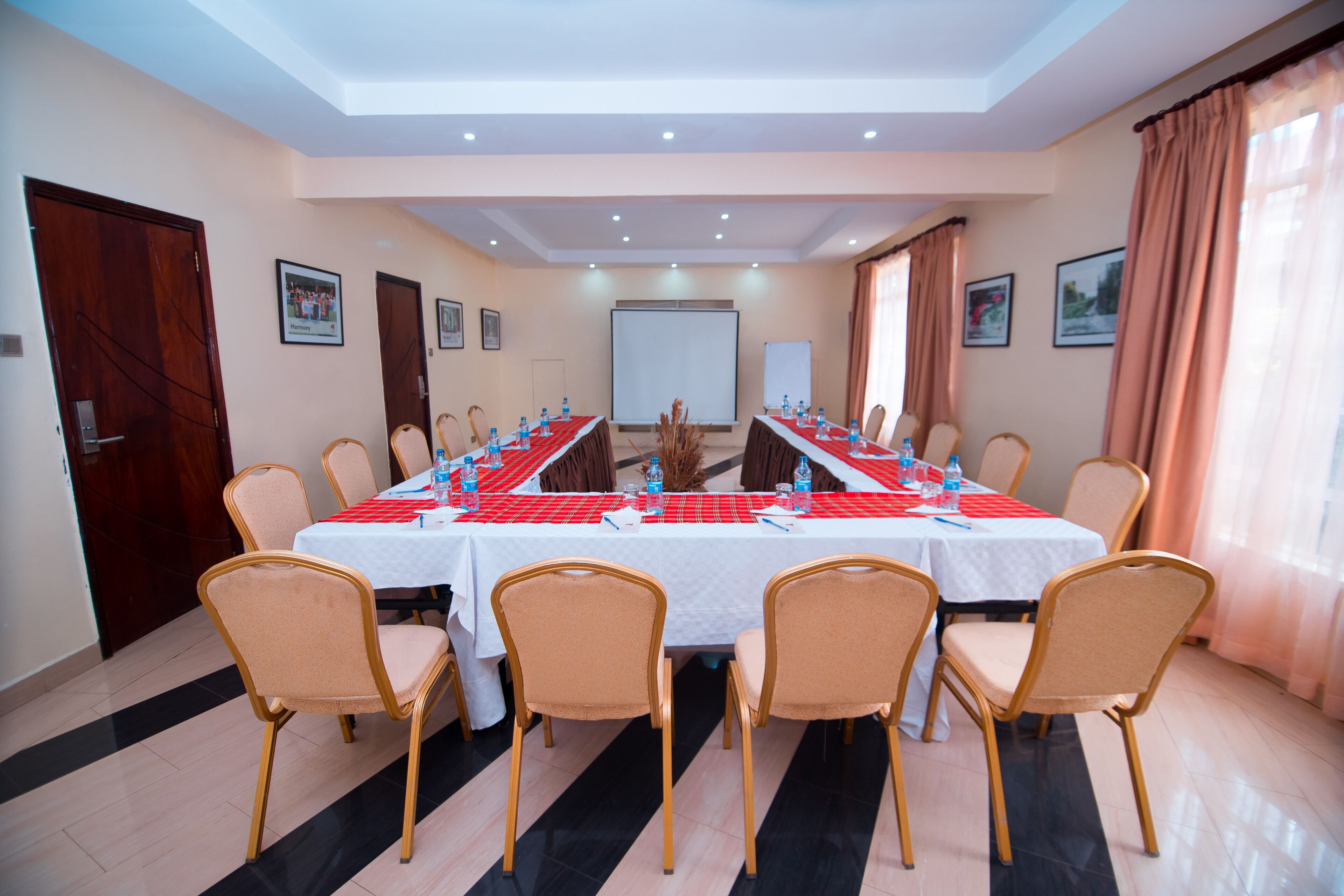 A conference room with a long table, chairs, and a projector screen.