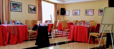 A conference room with multiple tables, chairs, and a projector screen.