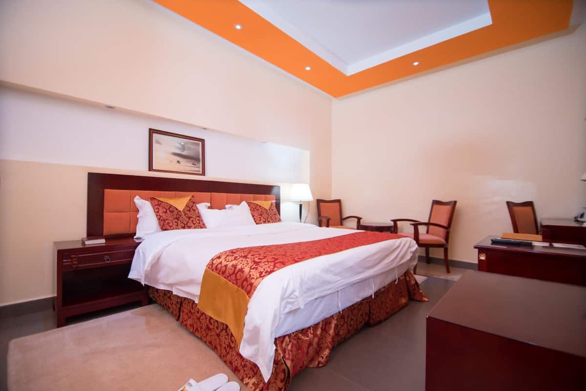 A hotel room with a large bed, a desk, and a chair.