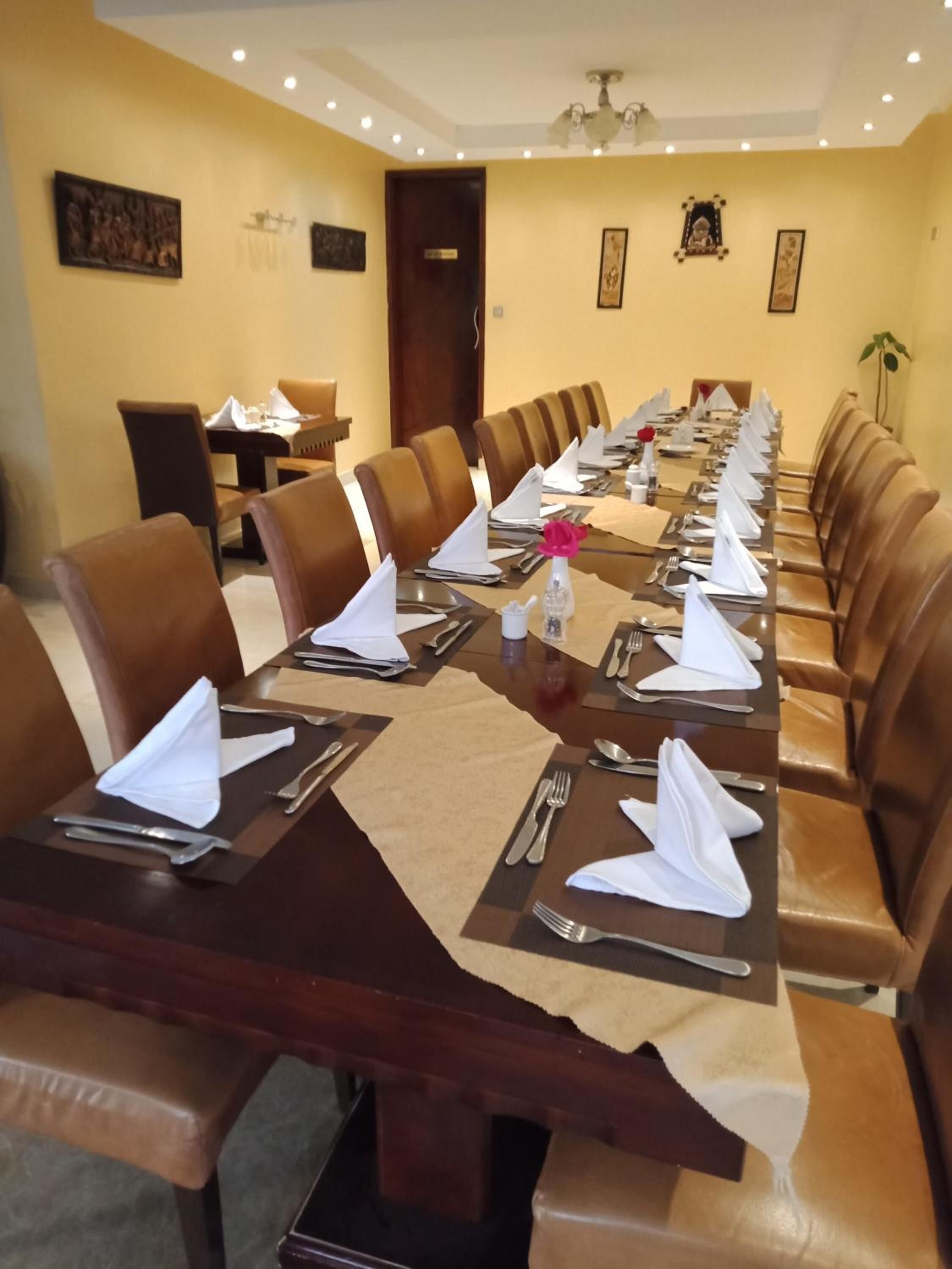 A conference room with a long table set for a meeting, surrounded by leather chairs.