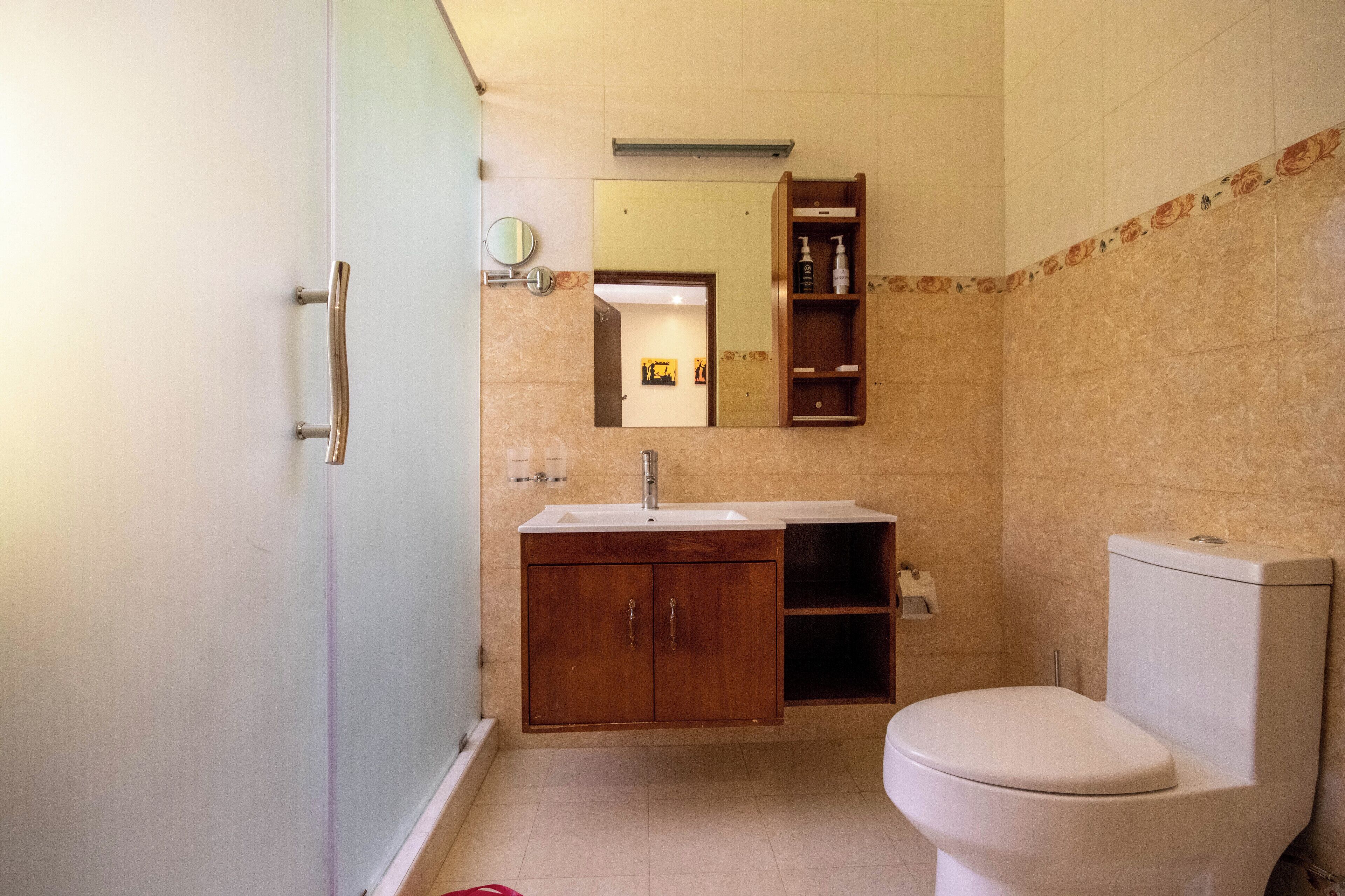 A bathroom with a toilet, sink, and mirror.