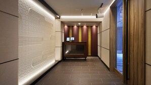 A hallway with a reception desk, patterned walls, and a view through a window. - Minn Kamata (Tokyo)
