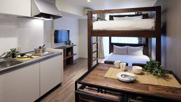 A compact hotel room with a bunk bed, kitchenette, and a small dining area.