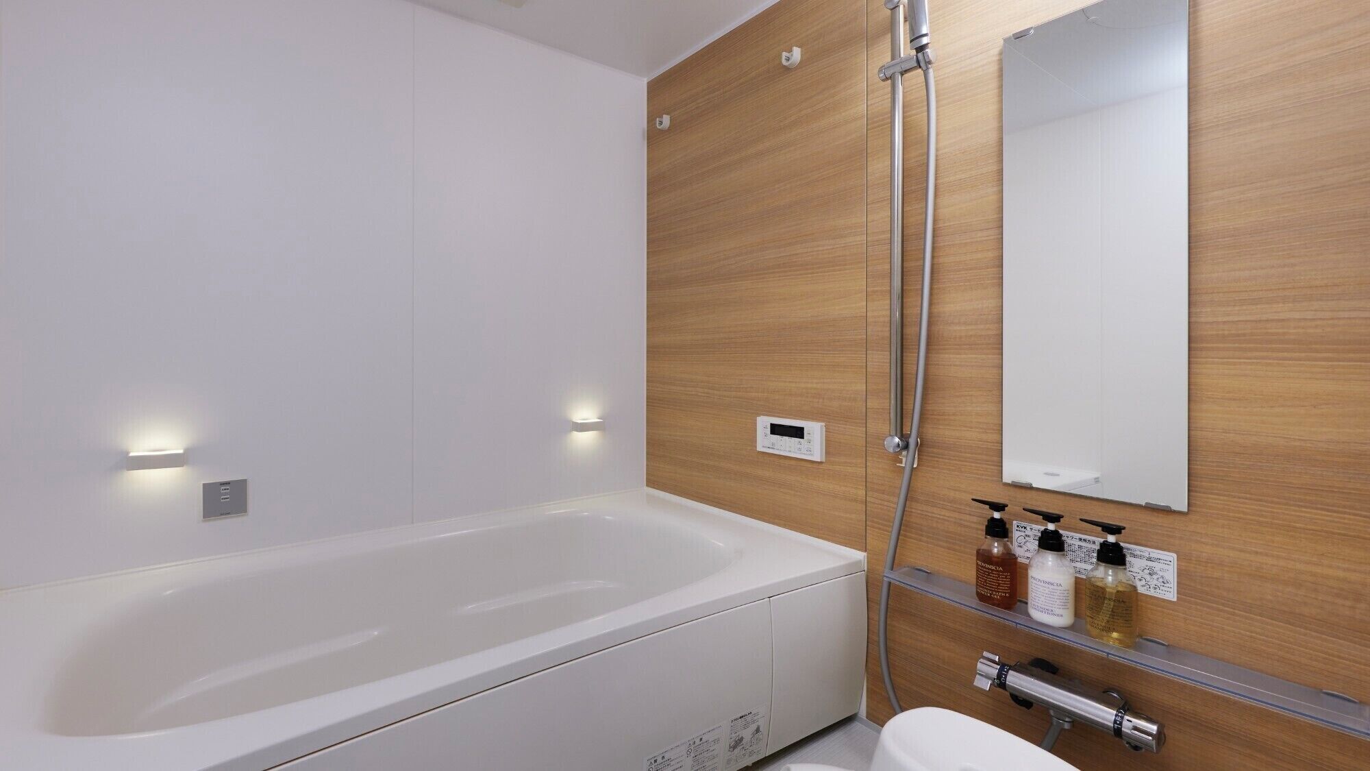 A modern bathroom with a white bathtub, wooden panel wall, and a mirror.