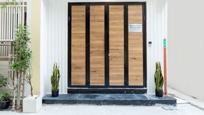 A wooden door with a sign above it, a potted plant to the left, and a potted plant to the right. - Cozrum Homes Charming Corner (Ho Chi Minh City)