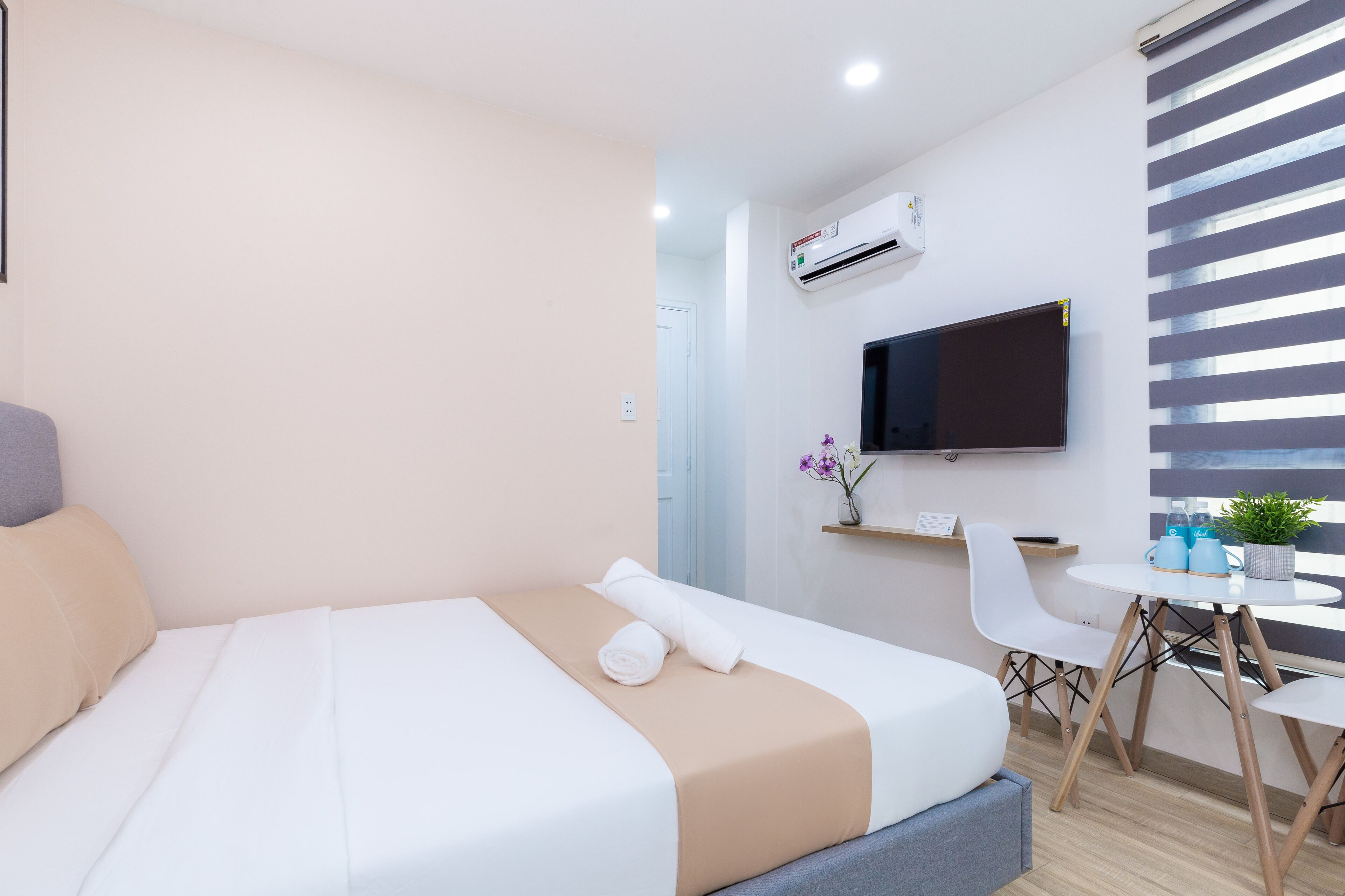 Quarto de hotel moderno com cama, escrivaninha e televisão.