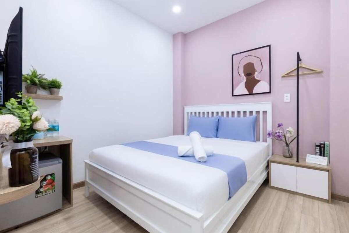A hotel room with a bed, bedside tables, a TV, and a wall-mounted artwork.