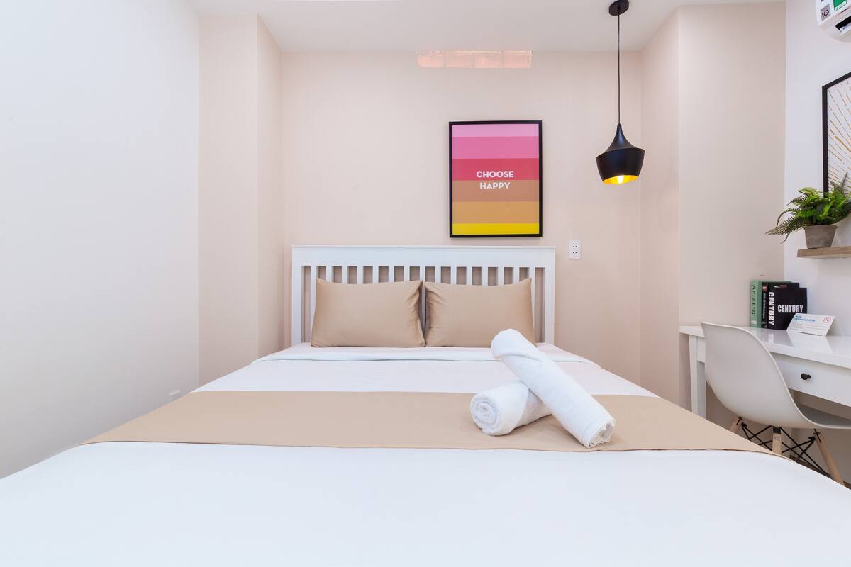 A neatly arranged hotel room with a bed, a desk, and a chair.