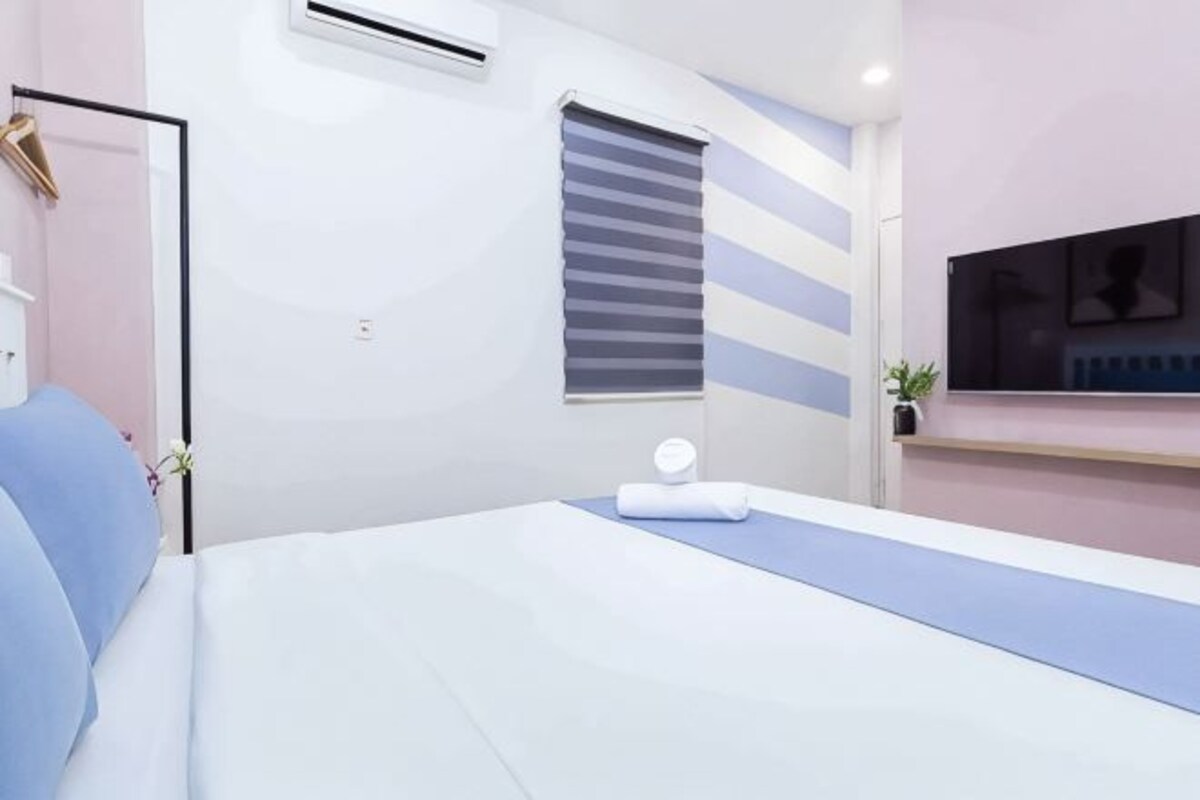 A modern bedroom with a bed, bedside table, and a window with blinds.