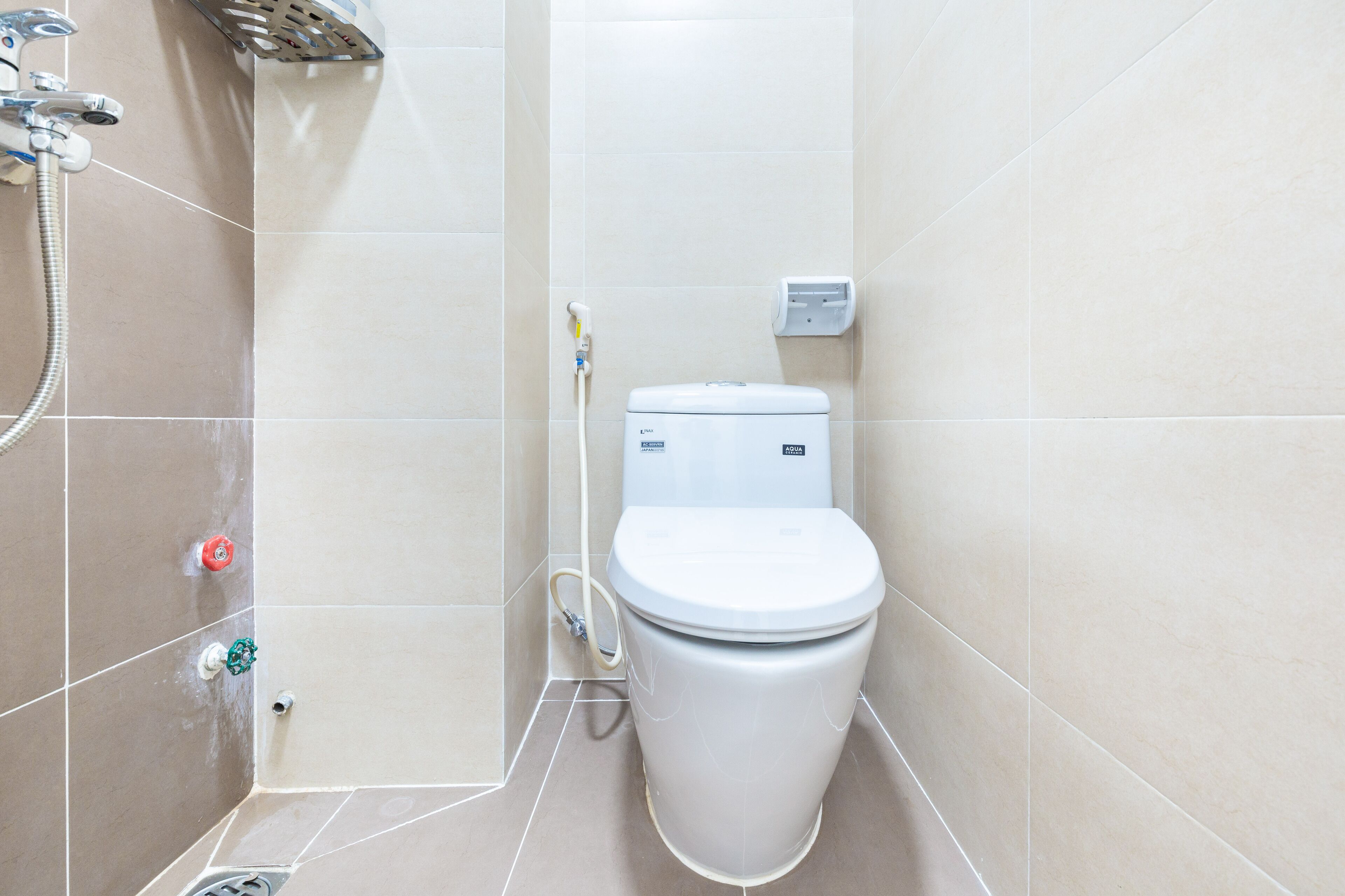 A bathroom with a toilet, a shower, and a hand dryer.