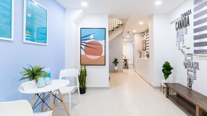A modern hotel lobby with a reception desk, seating area, and a staircase leading to upper floors. - Cozrum Homes Charming Corner (Ho Chi Minh City)