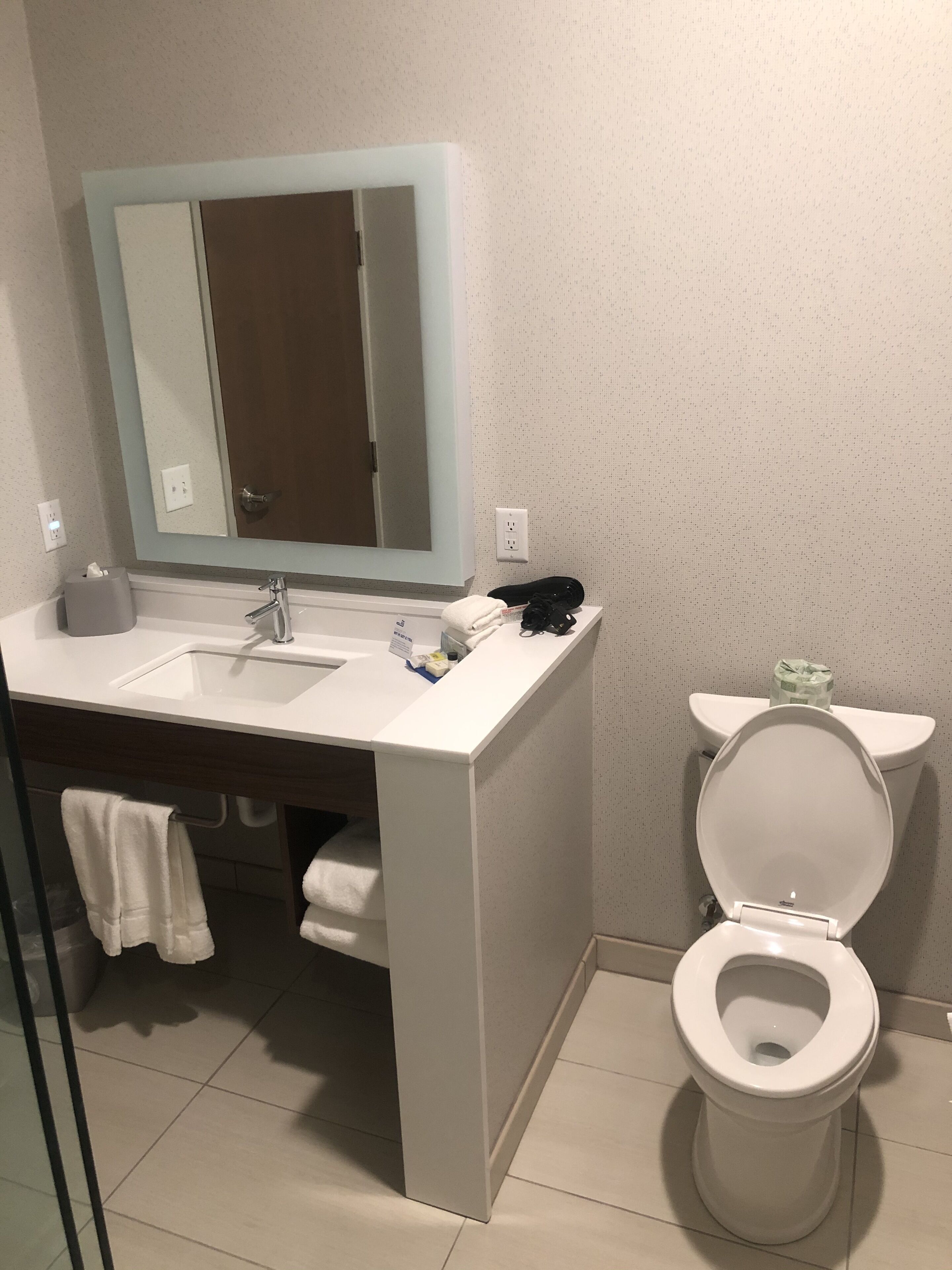 A bathroom with a white sink, mirror, and toilet.