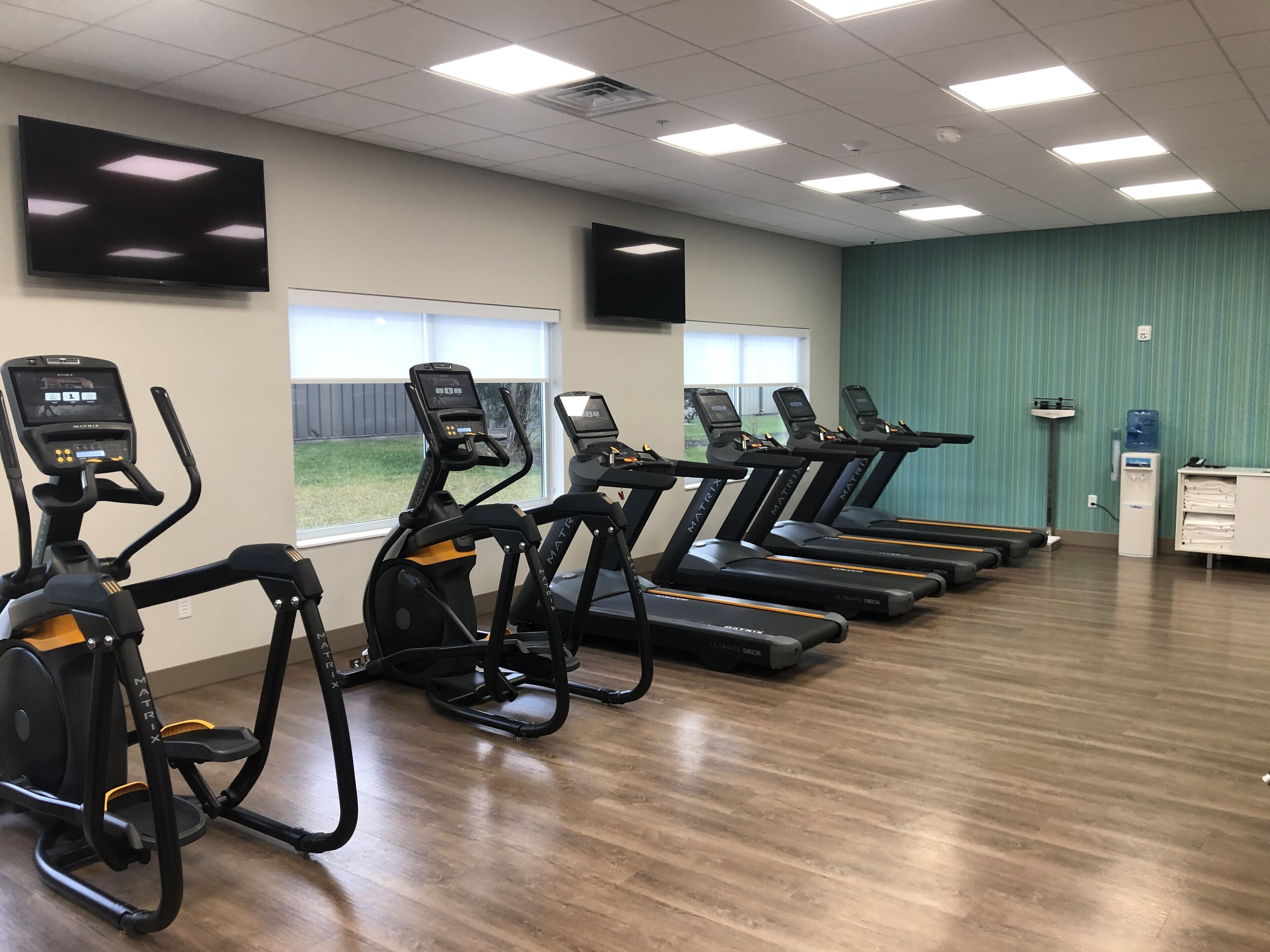Una sala de fitness amb cintes de córrer, una cinta el·líptica i una bicicleta estacionària.