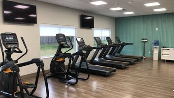 Una sala de fitness amb cintes de córrer, una cinta el·líptica i una bicicleta estacionària.