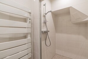 Eine moderne Dusche mit Bedienfeld, Glastür und Fliesenwand.