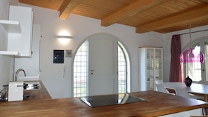 A kitchen with wooden beams, a white door, and a dining area with a table and chairs.