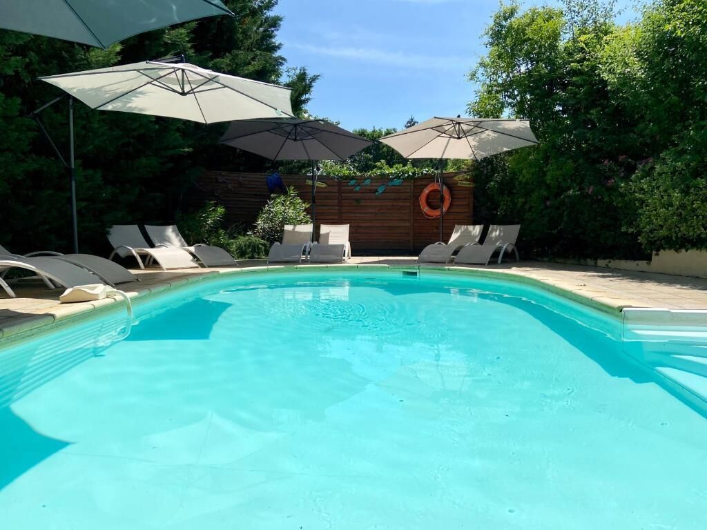 Une piscine avec des chaises longues et des parasols.