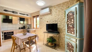 A compact kitchen with a dining area, a television, and a cabinet with floral designs. - Le Petit Prince - Espace bien être avec Spa - Piscine chauffée (Sarlat-la-Canéda)