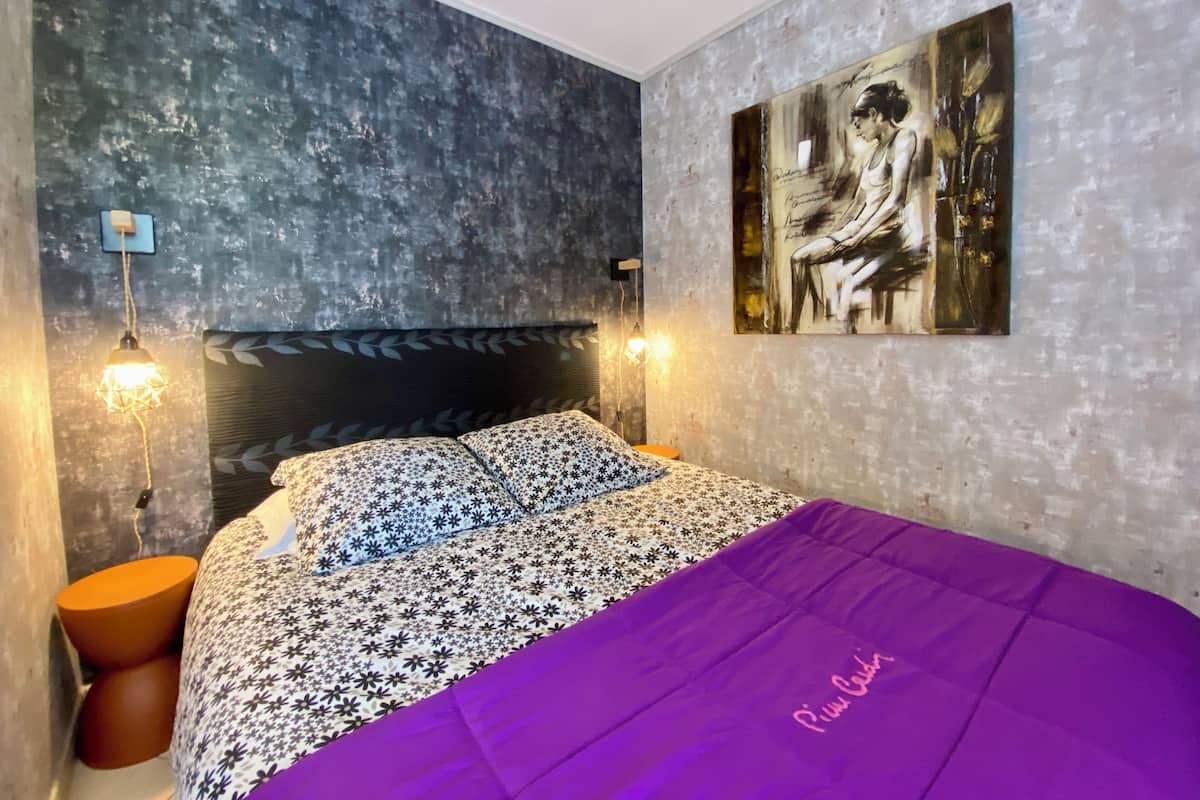 Quarto com cama, quadro na parede e parede texturizada.