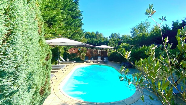 A swimming pool with lounge chairs and umbrellas, surrounded by greenery. - Le Petit Prince - Espace bien être avec Spa - Piscine chauffée (Sarlat-la-Canéda)
