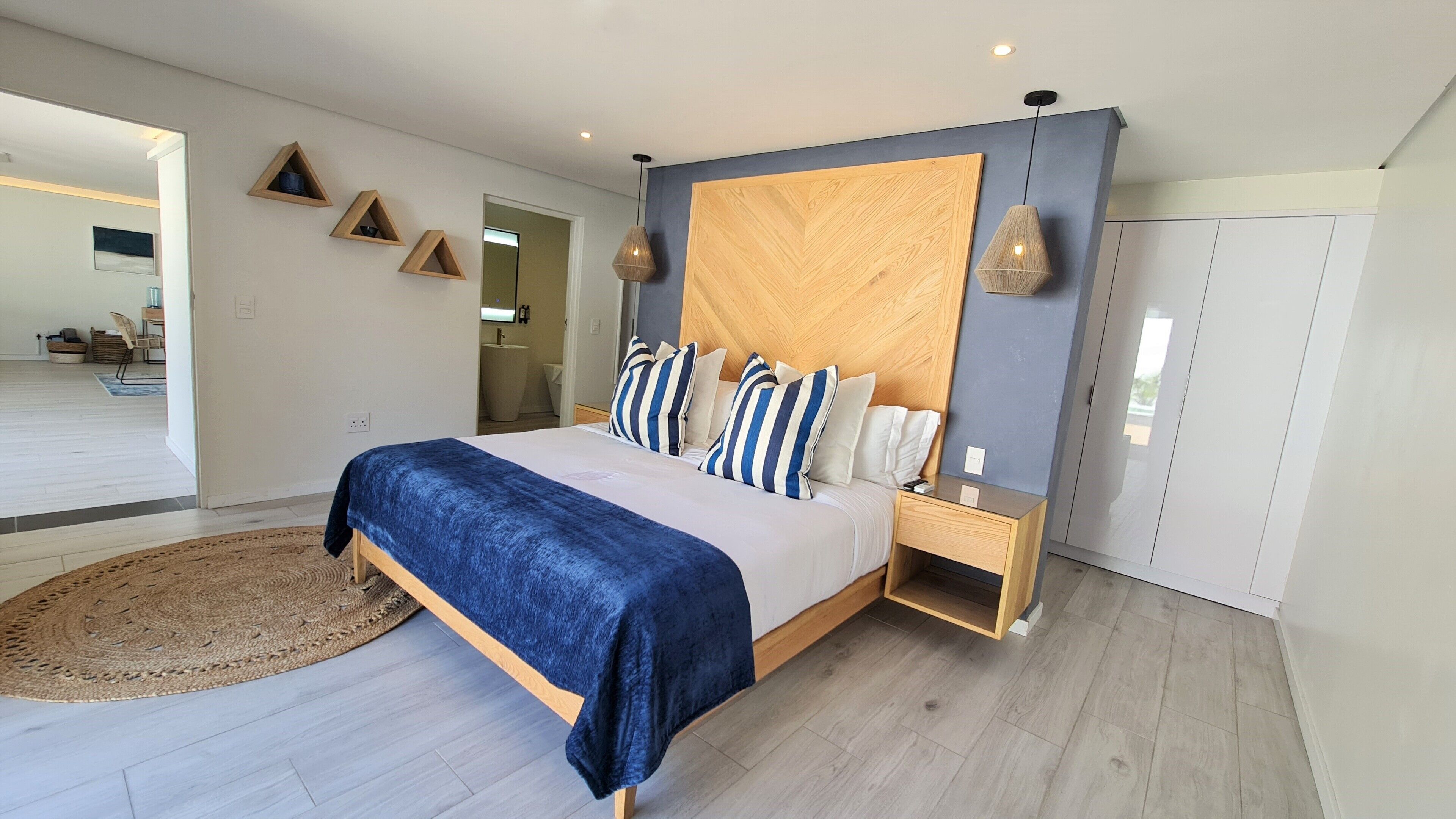 Een moderne slaapkamer met een groot bed, een houten hoofdbord en een nachtkastje.
