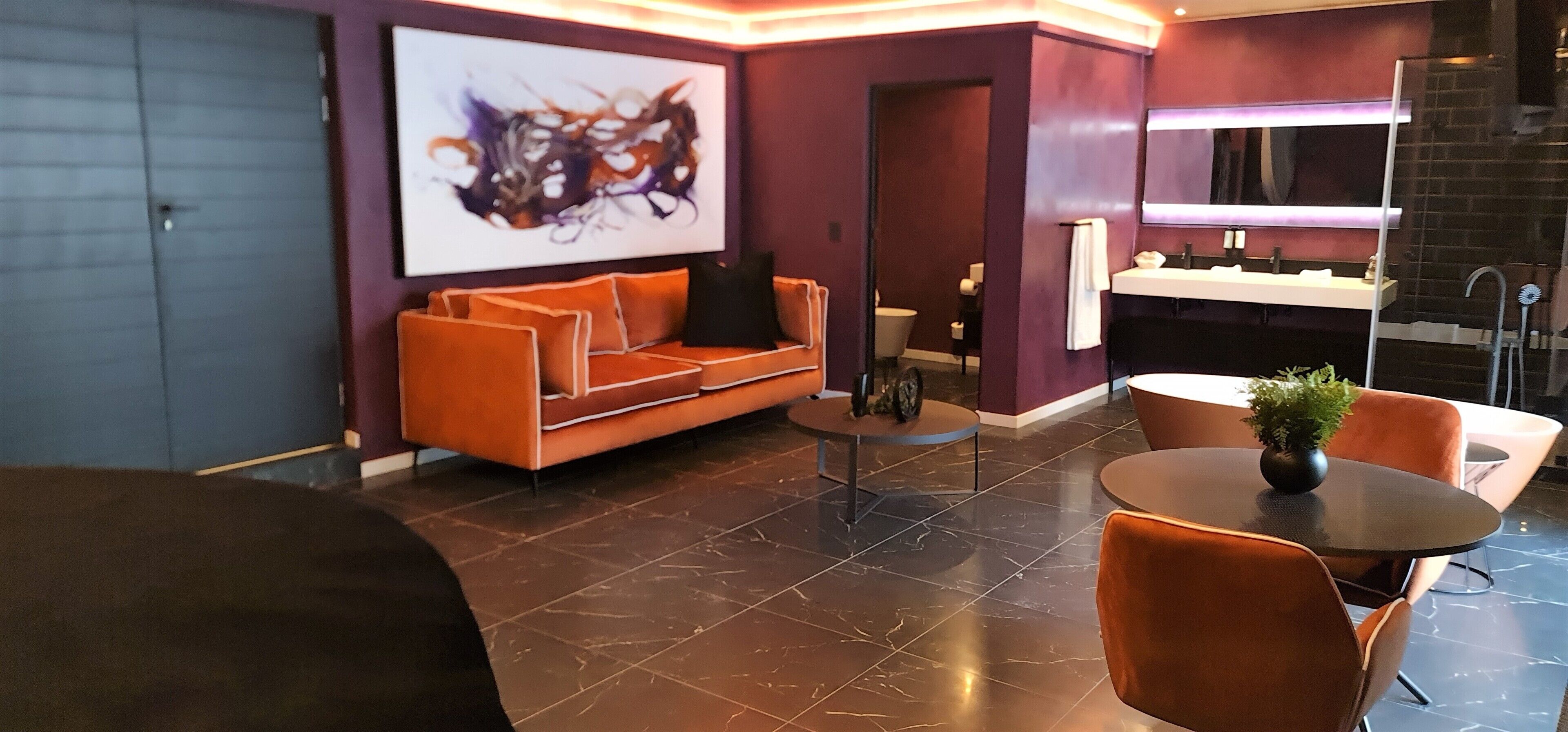 A modern living room with a sofa, a coffee table, and a dining area with chairs and a table.
