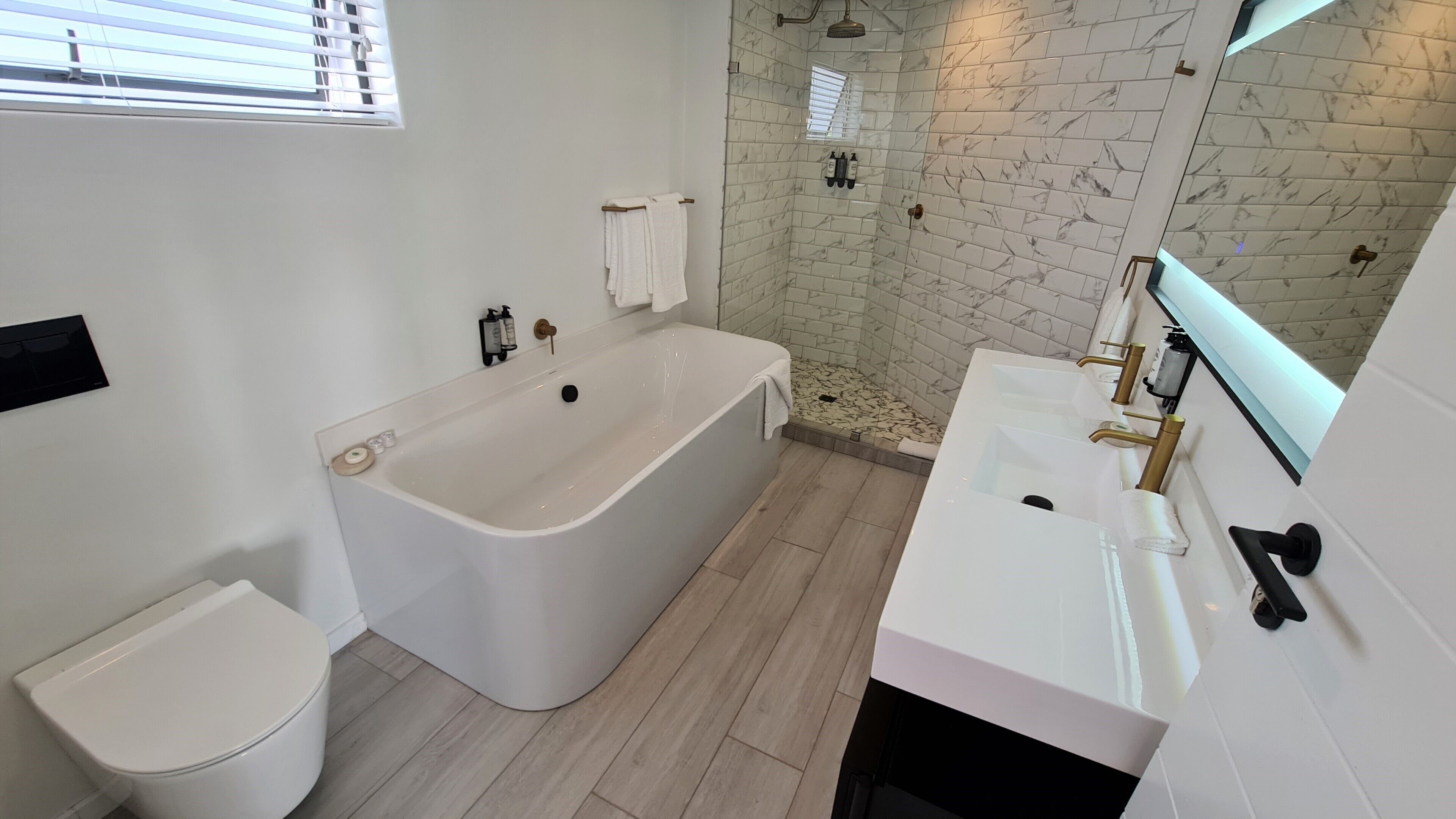 Un baño moderno con una bañera independiente, una zona de ducha separada y un lavabo con espejo.