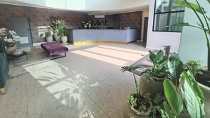 Eine geräumige Lobby mit einer Rezeption, einer Sitzecke und großen Kübelpflanzen.