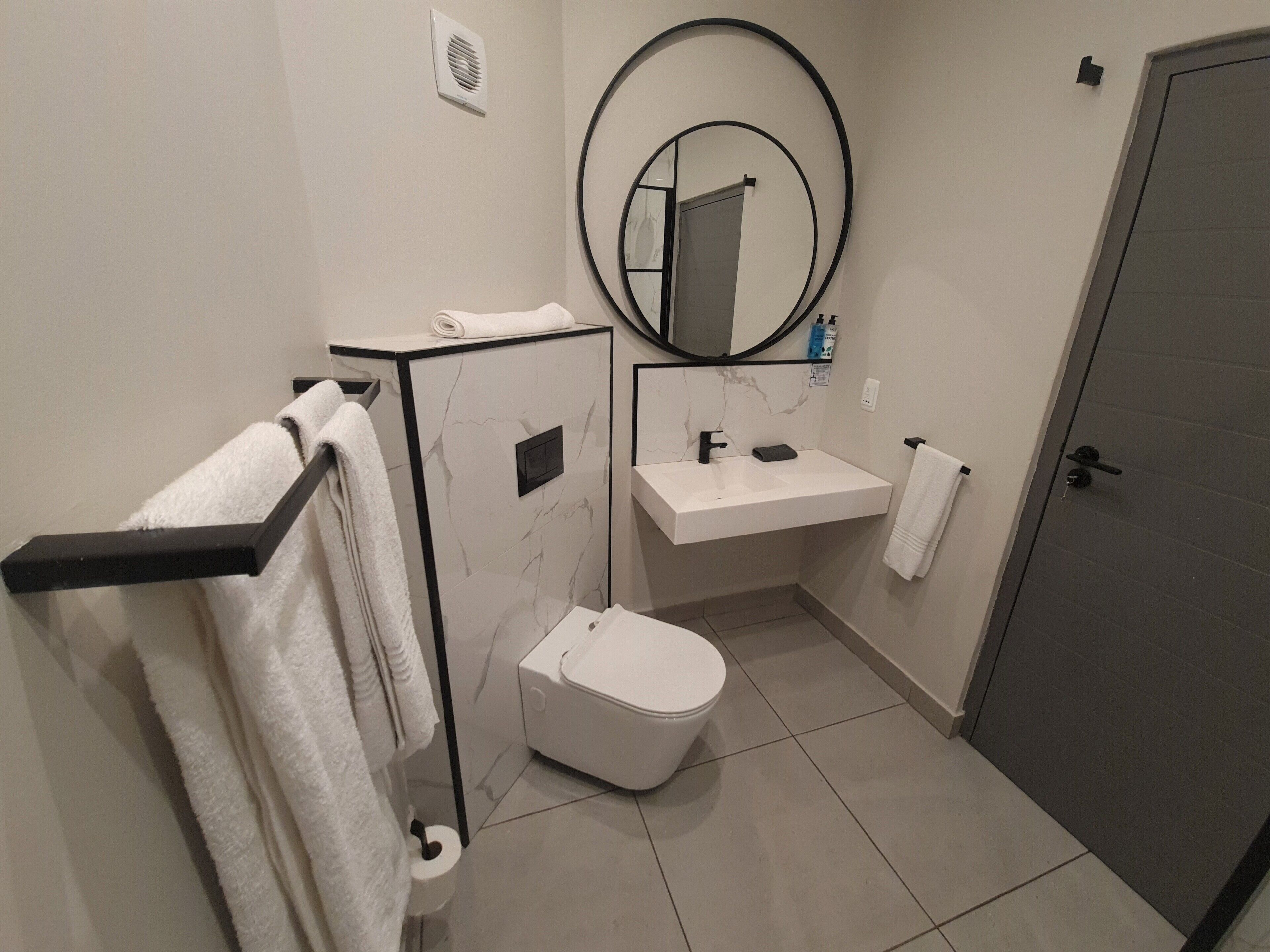 A modern bathroom with a toilet, sink, and towel rack.