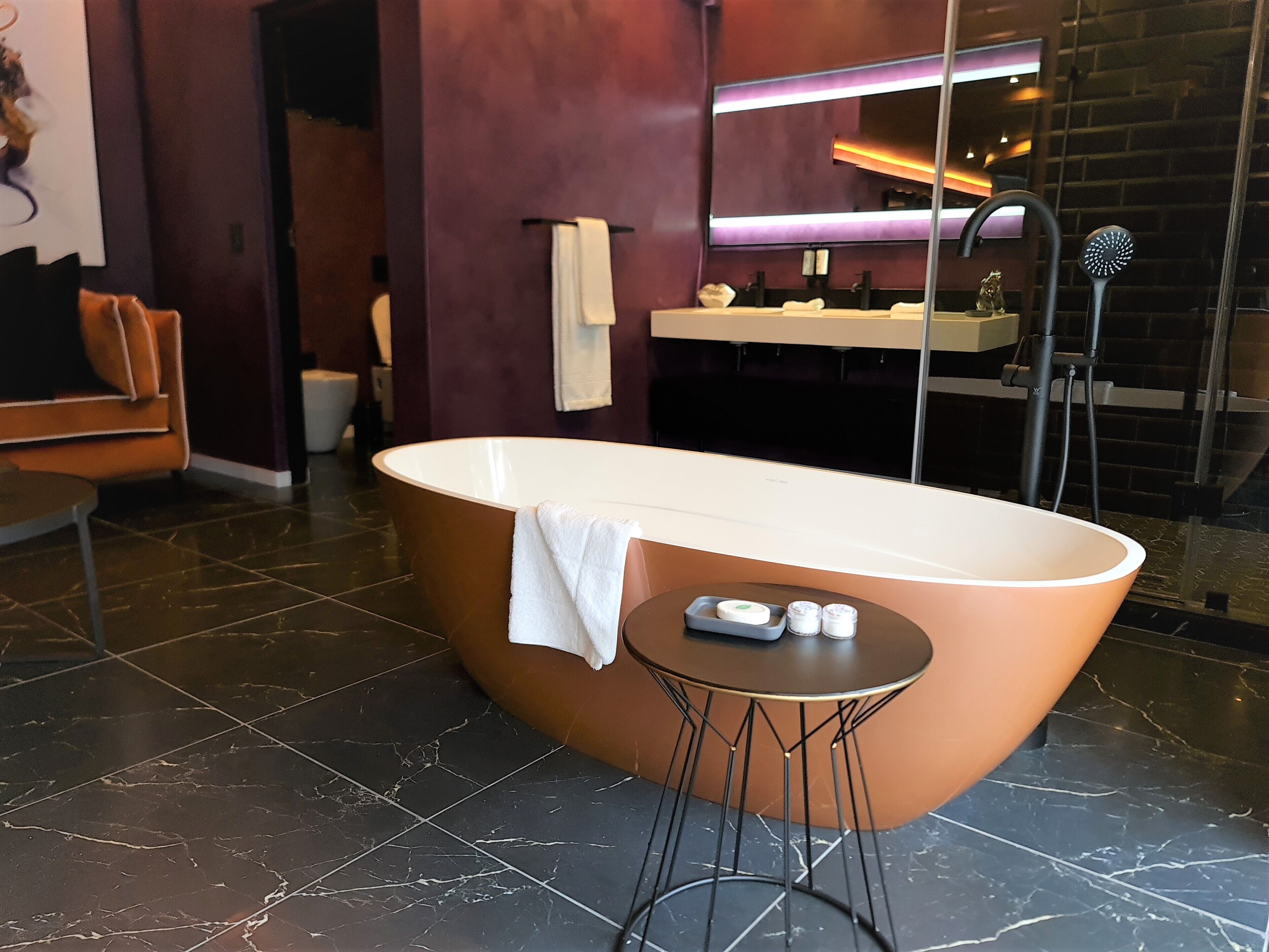 A modern bathroom with a freestanding bathtub, a vanity with a mirror, and a towel rack.