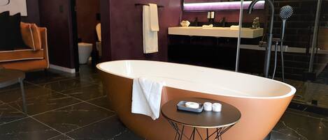 A modern bathroom with a freestanding bathtub, a vanity with a mirror, and a towel rack.