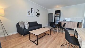A modern living room with a sofa, coffee table, and dining area.