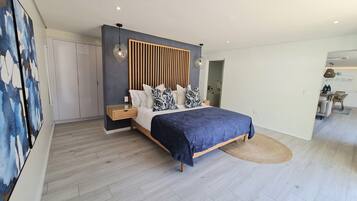 Un dormitorio moderno con cama, mesitas de noche y una lámpara fijada a la pared.