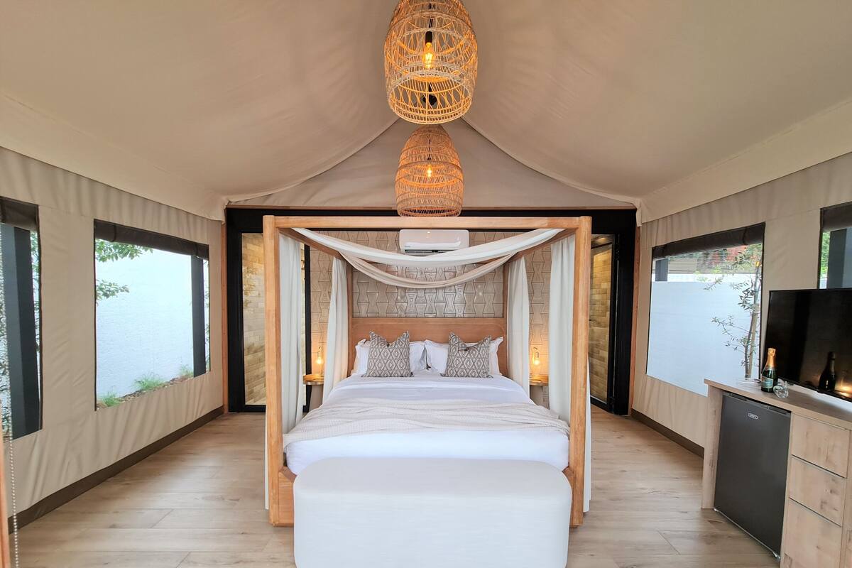 A spacious bedroom with a large bed, a canopy, a wooden desk, and a television.
