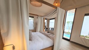 Ein geräumiges Schlafzimmer mit einem großen Bett, einem Nachttisch und Blick auf einen Swimmingpool.