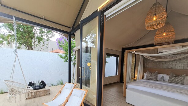 Ein modernes Schlafzimmer mit einem großen Bett, einem Hängesessel und einer Glastür zu einem Außenbereich mit H ängesessel und Tisch.