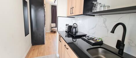 Uma cozinha moderna com bancada preta, pia de aço inoxidável e armários de madeira.