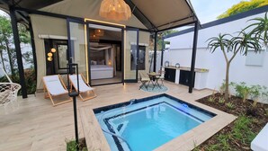 Ein moderner Außenbereich mit Pool, Liegestühlen und Essgruppe unter einer Markise.