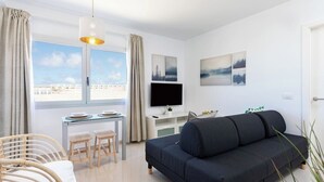 Una sala de estar moderna con sofá, mesa de comedor, sillas y televisor.