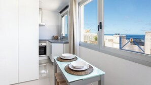 Una cocina moderna con comedor, ventanas amplias y vista al mar.