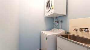 A compact laundry area with a washing machine, a dryer, and a sink with two faucets.