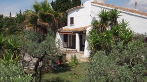 A white building with a tiled roof, surrounded by lush greenery and trees. - Holiday flat of the size of 45 m² on a large estate with pool close to Arles (Arles)