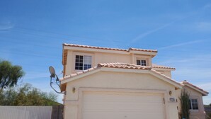 Ein eingeschossiges Haus mit Garage, Satellitenschüssel und strahlend blauem Himmel.