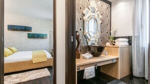 A modern bedroom with a bed, bedside table, and a mirror. - MURANO Suites | COBALT (Venezia)