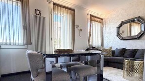 A living room with a dining table, chairs, a sofa, a coffee table, and a decorative mirror. - MURANO Suites | COBALT (Venezia)