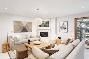 A modern living room with a sofa, armchairs, a coffee table, and artwork on the walls.